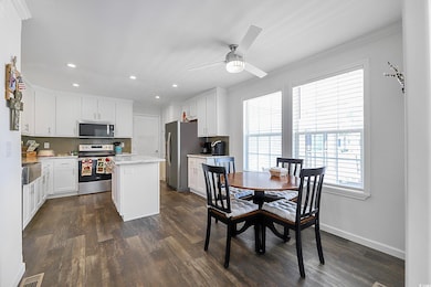 Kitchen with recessed lighting, white cabinets, stainless steel appliances, a kitchen island, and dark wood-type flooring