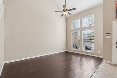 Spare room with high vaulted ceiling, dark wood-type flooring, and a ceiling fan