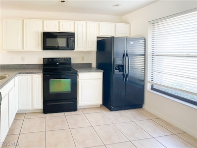 Kitchen with black appliances, dark countertops, and white cabinets