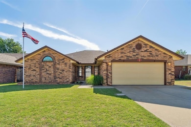 View of front of house featuring brick siding, a garage, driveway, a front lawn, and roof with shingles