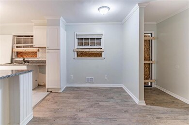 Kitchen with white cabinets, crown molding, light wood-style floors, tasteful backsplash, and stone counters