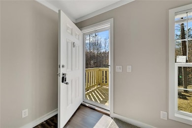 Doorway with dark wood-style flooring and baseboar