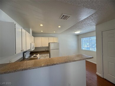 Kitchen with white appliances, a peninsula, a text