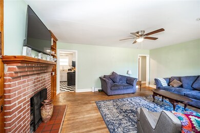 Living room featuring a fireplace, ceiling fan, and dark hardwood / wood-style floors