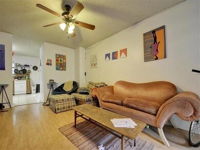 Living area with light wood-style floors, a textured ceiling, and a ceiling fan