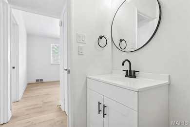Half bath with light wood-style flooring and vanity