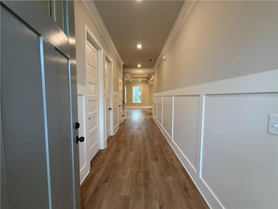 Hallway featuring ornamental molding, a decorative wall, dark wood-style floors, a wainscoted wall, and recessed lighting