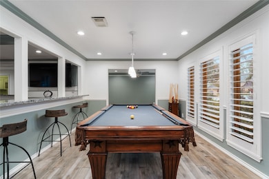 Enjoy quality time with loved ones in the spacious formal living (currently used as a game room), where neutral decor and wooden flooring create a cozy atmosphere for play and relaxation.