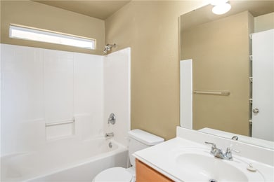 Bathroom featuring vanity, a textured wall, and  shower combination