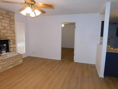 Unfurnished living room featuring a fireplace, light wood-style floors, ceiling fan, and a textured ceiling