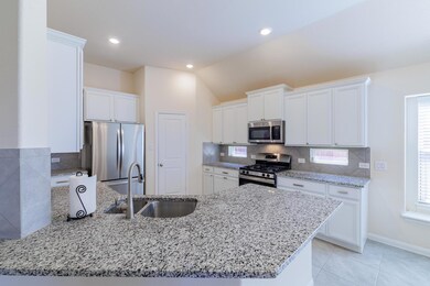 Kitchen with a sink, white cabinets, appliances w