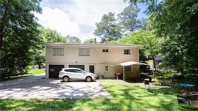 Rear view of property with asphalt driveway, a garage, and a lawn