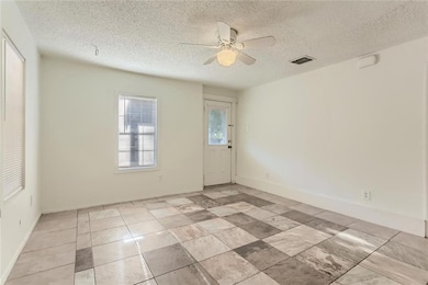 Spare room with ceiling fan, a textured ceiling, 