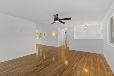 Spare room featuring wood finished floors, a ceiling fan, and a chandelier