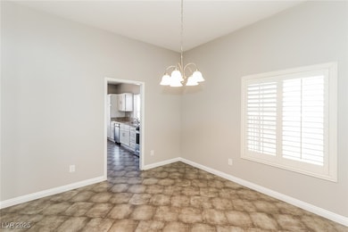 Spare room featuring baseboards, a chandelier, til