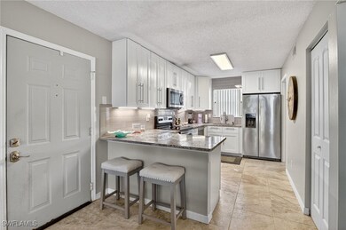 Kitchen featuring stainless steel appliances, a peninsula, backsplash, white cabinets, and a textured ceiling