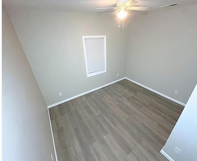 Spare room featuring dark wood-style flooring and ceiling fan