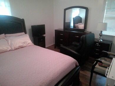 Bedroom featuring multiple windows and dark hardwood / wood-style flooring