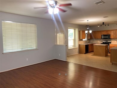 Kitchen with a kitchen island, tasteful backsplash, light countertops, black appliances, and pendant lighting