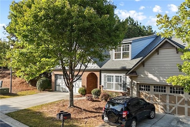 View of front of home with a shingled roof, driveway, an attached garage, and brick siding