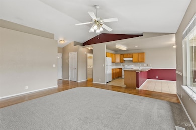 Kitchen featuring open floor plan, light countertops, white appliances, lofted ceiling, and a ceiling fan