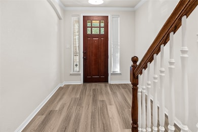 Entrance foyer with crown molding and light wood finished floors