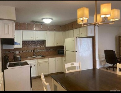 Kitchen with a sink, backsplash, freestanding refrigerator, and white cabinetry