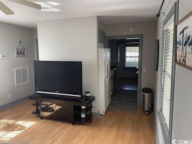 Corridor featuring a textured ceiling and light wood-style floors
