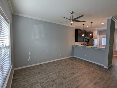 Unfurnished living room featuring ornamental molding, ceiling fan, and dark wood-style floors