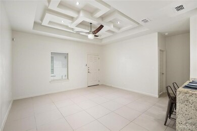 Empty room featuring light tile patterned floors, coffered ceiling, visible vents, baseboards, and a ceiling fan
