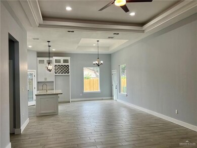 Empty room with light hardwood / wood-style flooring, ceiling fan with notable chandelier, a raised ceiling, and sink