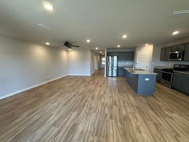 Kitchen with appliances with stainless steel finishes, open floor plan, a ceiling fan, wood finished floors, and an island with sink