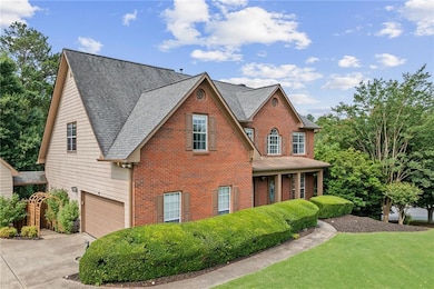 View of front of home featuring brick siding, driveway, a garage, and roof with shingles