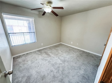 Carpeted spare room featuring baseboards and ceiling fan