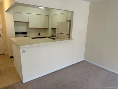 Kitchen with light countertops, freestanding refrigerator, range with electric stovetop, a peninsula, and light colored carpet