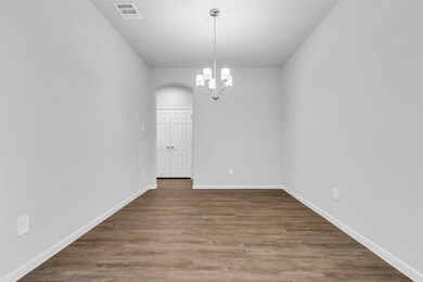 This is the dining room, featuring durable vinyl plank flooring and a clean, modern look. The open doorway at the far end provides a seamless transition into the kitchen, creating an easy flow for everyday meals and entertaining.