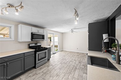 Kitchen featuring rail lighting, appliances with stainless steel finishes, a textured ceiling, light wood-style flooring, and white cabinetry