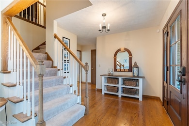 Foyer featuring light wood-style floors, a chandelier, and a textured ceiling