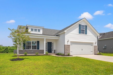 View of front facade with brick siding, driveway, a front lawn, and board and batten siding
