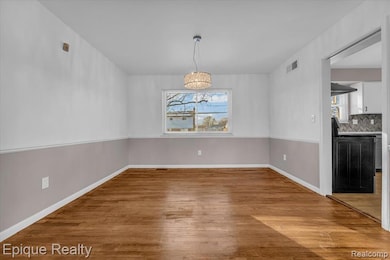 Unfurnished dining area with light wood-style floors and baseboards
