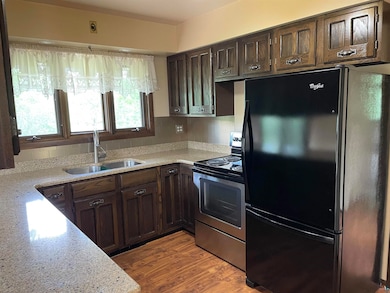 Kitchen with freestanding refrigerator, stainless steel range with electric stovetop, a sink, dark brown cabinetry, and backsplash