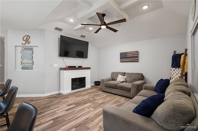 Living room featuring lofted ceiling with beams, hardwood / wood-style floors, and ceiling fan