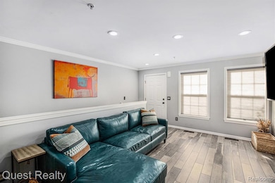 Living room featuring ornamental molding, wood-type flooring, and recessed lighting