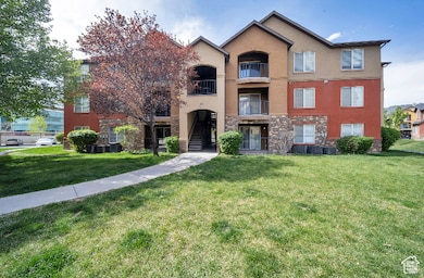 View of front of house featuring stone siding, a balcony, stucco siding, a front lawn, and stairs