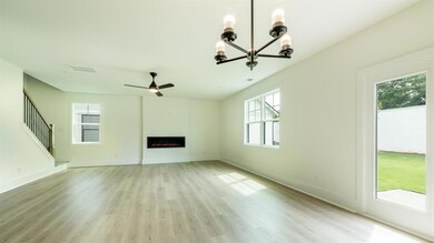 Unfurnished living room featuring a chandelier, plenty of natural light, light wood-type flooring, and a ceiling fan
