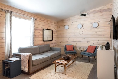 Living area featuring wood walls, vaulted ceiling