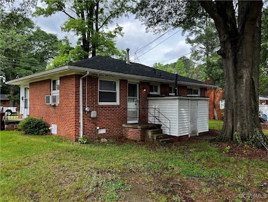 Back of house with brick siding, a lawn, and cooli