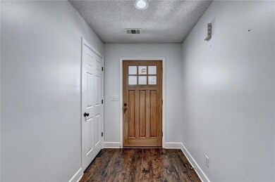 Doorway to outside featuring a textured ceiling and dark wood-style floors