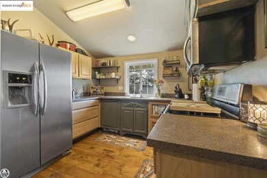 Kitchen with light brown cabinets, wood-type flooring, sink, lofted ceiling, and appliances with stainless steel finishes