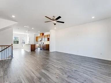 Unfurnished living room featuring dark wood-style flooring, recessed lighting, and ceiling fan